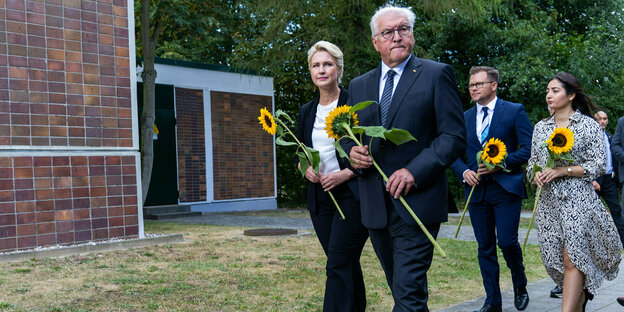 Bundespräsident Frank-Walter Steinmeier und andere Personen mit Sonnenblume in de rHand.
