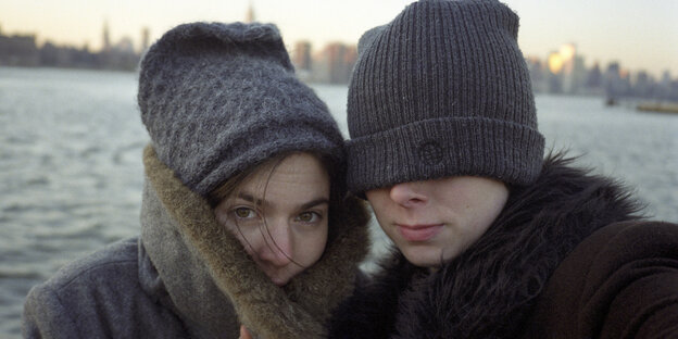 Portrait zweier frierender Menschen, die dicke Jacken und Mützen tragen vor dem East River in Brooklyn