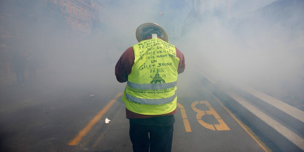 Ein Mann in gelber Weste im Nebel auf einer Straße