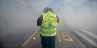 Ein Mann in gelber Weste im Nebel auf einer Straße