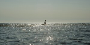 Ein einsamer mensch steht bei Sonnenuntergang im weiten Meer