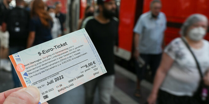 Ein Mensch hält ein 9-Euro-Ticket in die Kamera