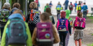 Kinder mit Schulränzen auf dem Weg zur Schul