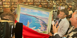Macron schaut auf ein Gemälde der Hafenstadt Oran