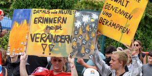 Eine Demonstrierende Person hält bei einer Gedenk-Demo ein Schild, auf dem steht: "Erinnern heißt verändern!"