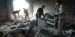 Menschen räumen in einem zertrümmerten Wohnhaus auf