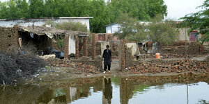 EIn Mann steht vor seinem von den Fluten zerstörten Haus