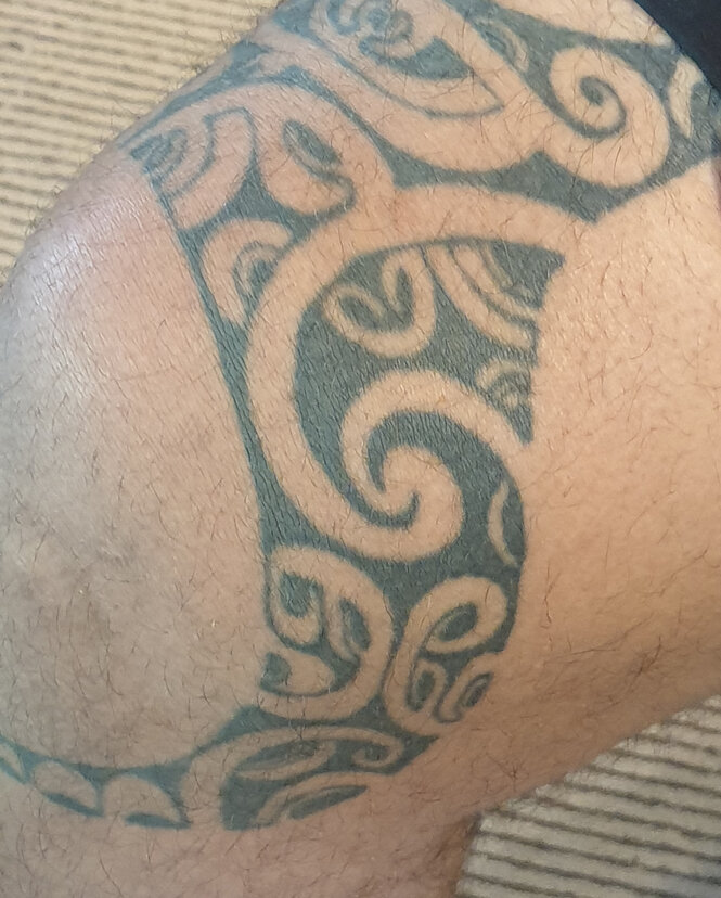 Ein aus Mustern bestehendes Tatoo rund um das Knie von einem Mann