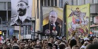 Eine Menschenmenge, die Menschen tragen unter anderem ein Transparent mit einem Bild von Wladimir Putin