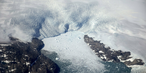 Luftaufnahme eines Gletschers, dessen Eis sich in eine Meeresbucht ergießt