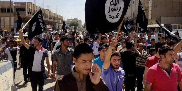 Männer demonstrieren mit einer IS-Fahne