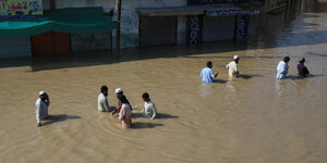 Menschen waten durch eine überflutete Straße