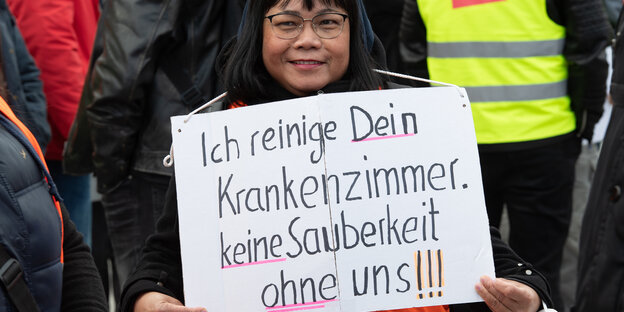 Eine Pflegekraft von Vivantes hält ein Schild mit der Aufschift "Ich reinige Dein Krankenzimmer. Keine Sauberkeit ohne uns!!" bei einer Demonstration von Vivantes und deren Töchterunternehmen vor dem Roten Rathaus.