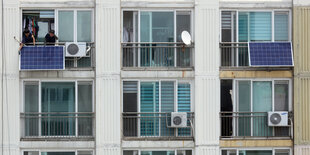 Balkone mit einzelnen Balkonsolaranlagen, Arbeiter montieren eine Anlage