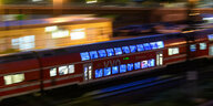 Ein Zug mit beleuchteten Fenstern saust durch die Nacht