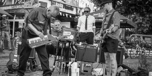 Vier Männer spielen auf einem Platz ein Konzert