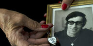 Eine Frauenhand hält ein Porträt von André Spitzer und ein Herzchen