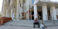 Ein Bauarbeiter sitzt vor einem beschädigten Gebäude