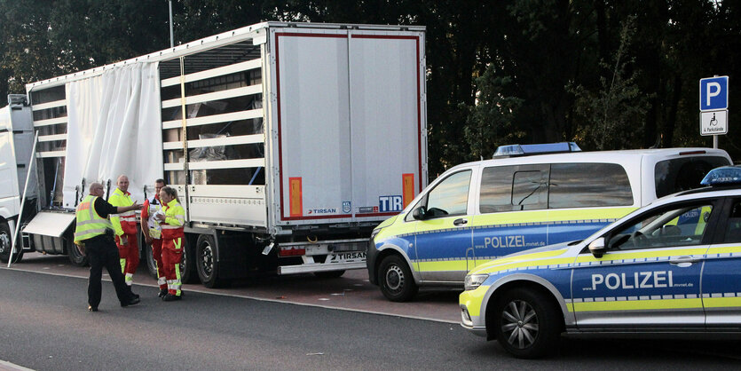 Ein Polizist und Mitarbeiter des Rettungsdienstes diskutieren vor einem Sattelauflieger auf der Raststätte Stolpe Nord (Fahrtrichtung Hamburg) an der Autobahn A 24