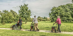 Rentner spazieren mit Rollator in Grünen