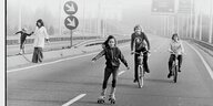 Kinder fahren Fahrrad und Rollschuhe auf einer Autobahn