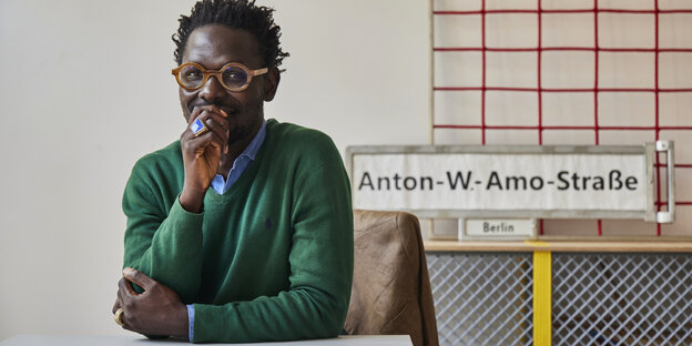 Ibou Diop im Büro der "Dekoloniale", im Hintergrund das Schild "Anton-W.-Amo-Straße", nach der die Berliner "Mohrenstraße" umbenannt werden soll