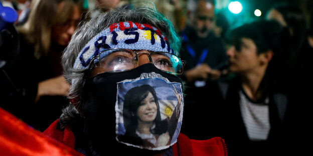 Eine Frau mit einem Bild Kirchners auf ihrer Maske gedruckt protestiert