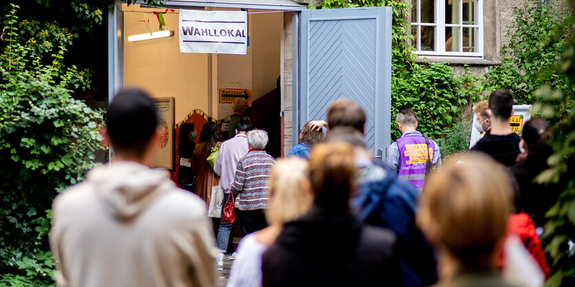 Menschen stehen Schlange vor einem Wahllokal