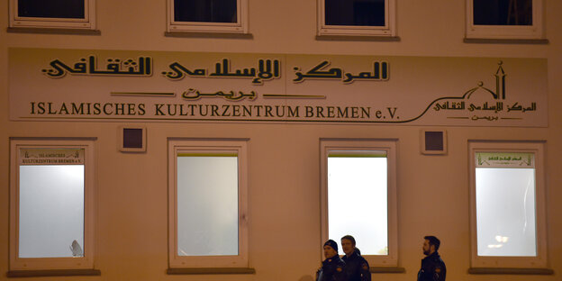 Polizisten vor einer Hauswand, auf der "Islamisches Kulturzentrum" steht