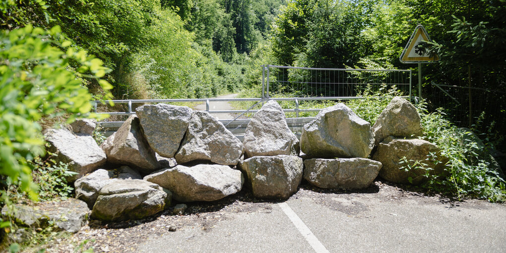 Große Feldsteine blockieren eine kleine Landstraße im Grünen