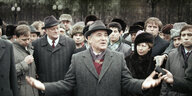 Michail Gorbatschow steht mit grauem Mantel und Hut in einer Menschenmenge