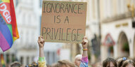 Demonstrierende halten ein Plakat hoch, auf dem "Ignorance is a Privilege" steht