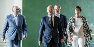 Scholz, Lindner, Esken und Nouripour gehen forschen Schrittes über einen Flur.