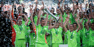 Die Spielerinnen des VfL Wolfsburg, noch in ihren Trikots auf dem Spielfeld, jubeln mit dem DHB-Pokal