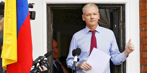Julian Assange steht in einer offenen Tür