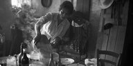Schwarz-Weiß-Foto: Die italienische Schauspielerin Sophia Loren gießt Spaghetti ab. Der Tisch steht voller Weinflaschen.