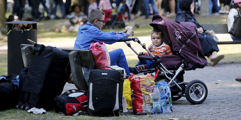 Ein Junge sitzt vor einem Kind in Kinderwagen