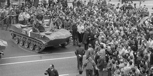 Historische Aufnahme von Demonstrant:innen und einem Panzer.