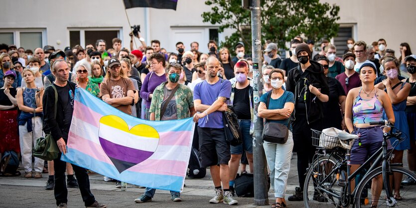 Eine Gruppe von Leuten hält ein Transparent mit einem in Trans-Farben gestreiften Herz