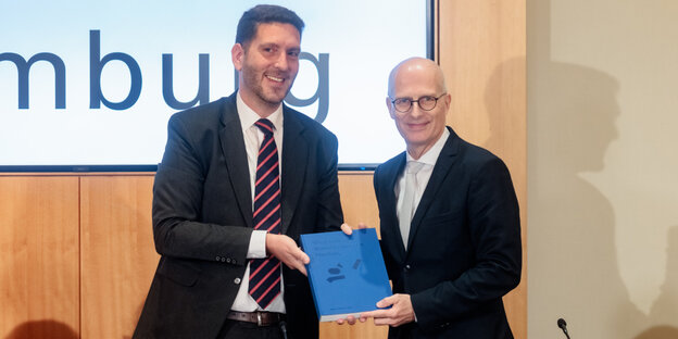 Philipp Stricharz, 1. Vorsitzende der Jüdischen Gemeinde Hamburg, und Bürgermeister Peter Tschentscher halten ein Exemplar der Machbarkeitsstudie zum Wiederaufbau der Bornplatzsynagoge in Händen. Philipp Stricharz, 1. Vorsitzende der Jüdischen Gemeinde Hamburg, und Bürgermeister Peter Tschentscher halten ein Exemplar der Machbarkeitsstudie zum Wiederaufbau der Bornplatzsynagoge in Händen.