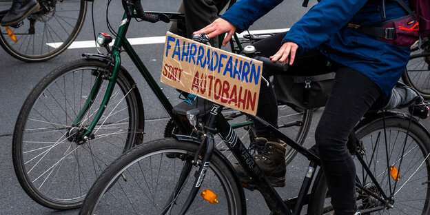 Ein Fahrradfahrer mit einem Schild: Fahrradfahren statt Autobahn