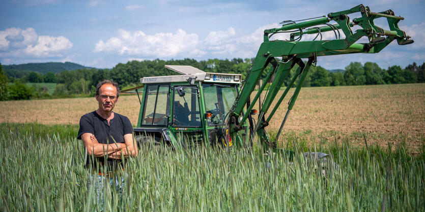 Mann vor Traktor auf einem Feld