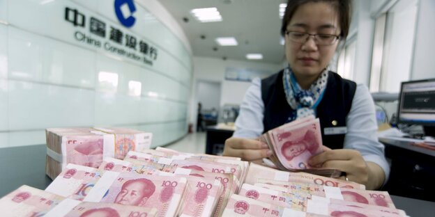 Ein Bankangestellte zählt 100 Yuan-Scheine.