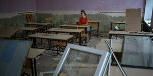 Eine Person in einem zerstörten Klassenzimmer.