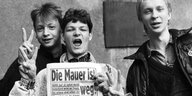 Jugendliche mit einer Zeitungstitelseite zum Mauerfall.