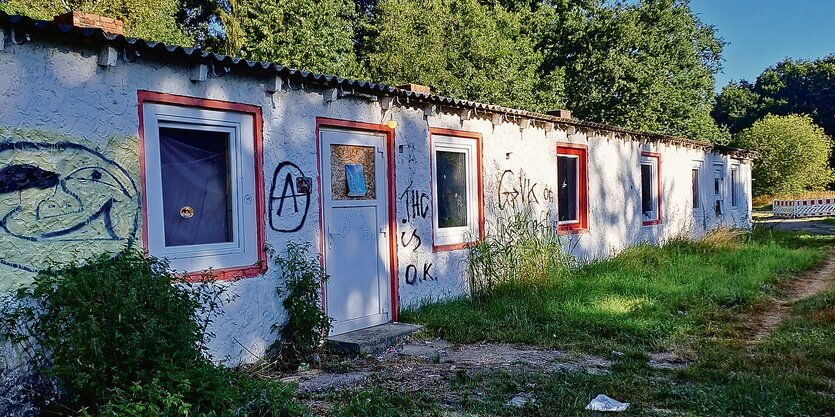 Eine eingeschossige Baracke mit Graffiti an den Wänden.