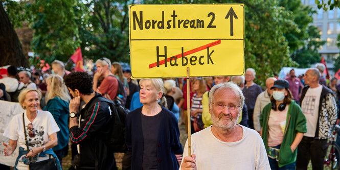 EIn Demonstrant hält ein Schild in Form eines Ortsausgangsschildes. Habeck ist durchgestrichen, der Pfeil zeigt in RIchtung Nord-Stream 2