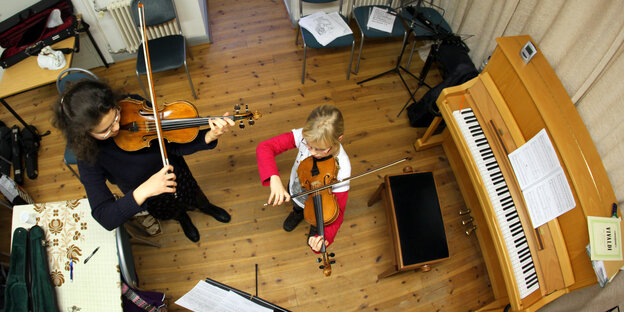 Eine Musikschülerin probt mit ihrer Musiklehrerin auf der Geige.