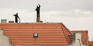 Schornsteinfeger arbeiten auf einem Hausdach.