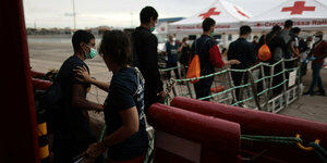 Migranten gehen im Hafen von Taranto (Italien) an Land.